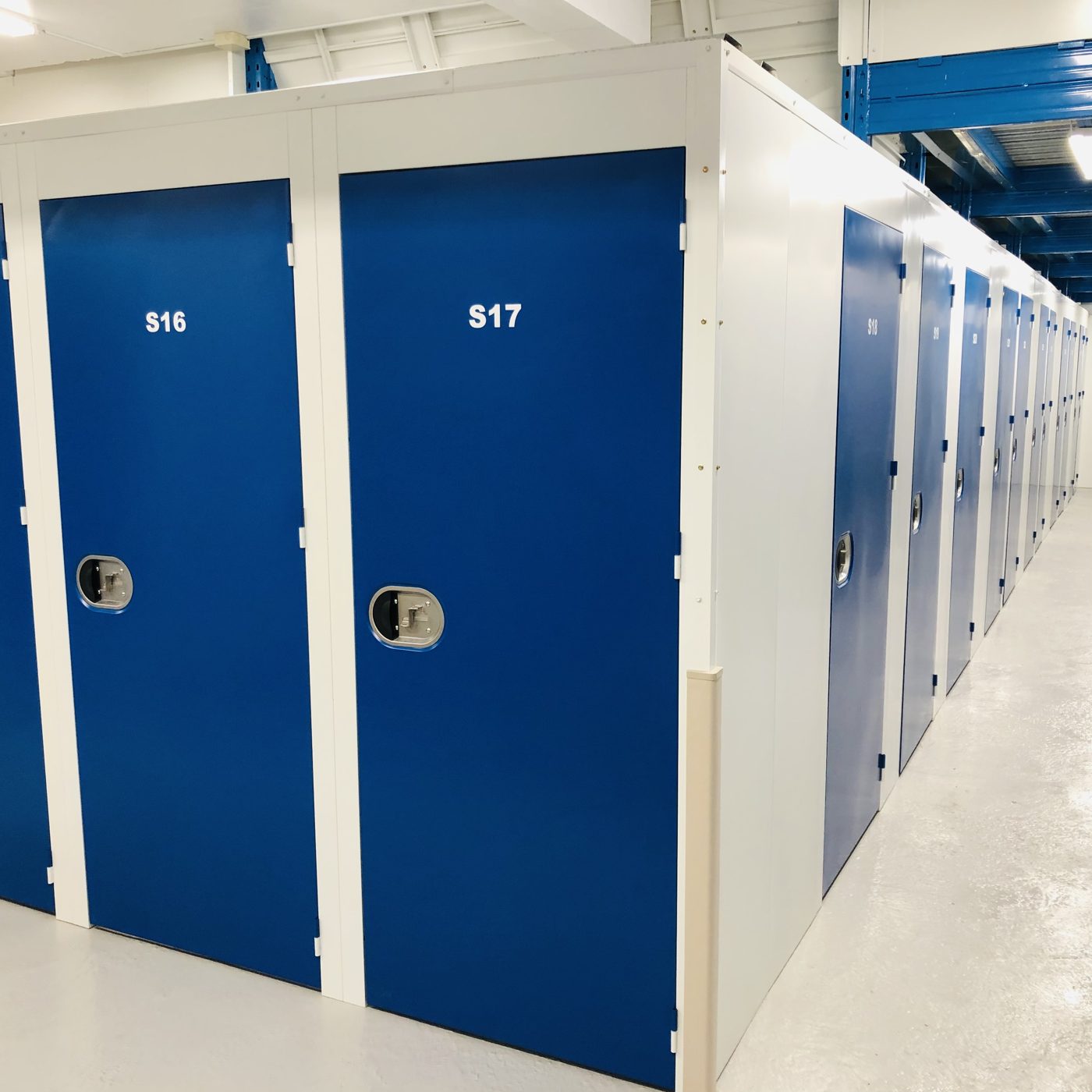 Bright, clean indoor storage hallway with blue unit doors